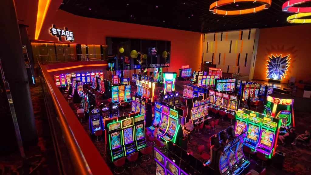 Casino floor with rows of slot machines and the Stage 954 entrance at The Casino @ Dania Beach.