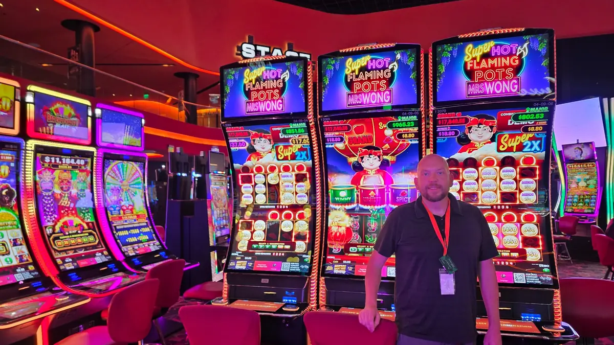 Wojtek in front of three Super Hot Flaming Pots Mrs. Wong slot machines at The Casino @ Dania Beach.